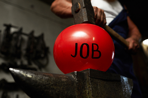 Blacksmith keeping heavy hammer on red inflated ball symbolizing job