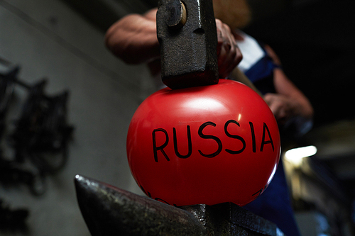 Blacksmith hammer on red inflated ball symbolizing Russia and showing its force