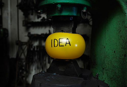 Yellow inflated ball with note idea between upper and lower parts of heavy iron machine