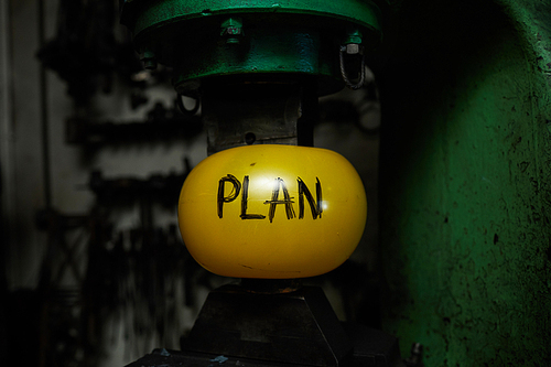 Plan in form of yellow inflated ball between two parts of industrial machine symbolizing its reliability