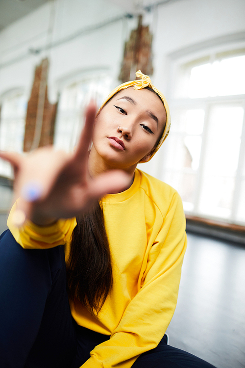 Young modern dance learner in yellow sweatshirt sitting on the floor in front of camera