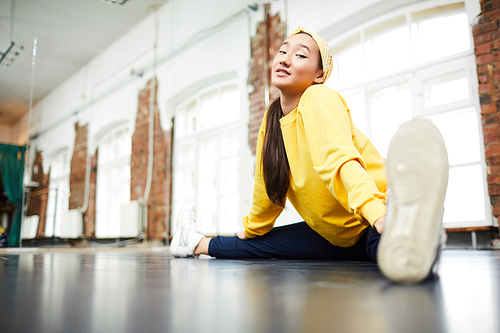 Young woman sitting in front of camera with her legs stretched during training