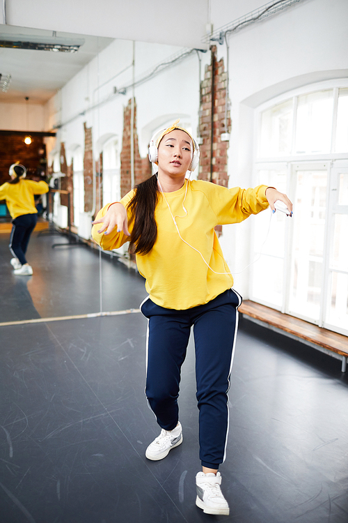 Young dancer in activewear learning hip hop motion during training in modern studio of dancing