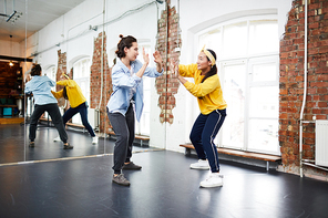 Hip hop dance learner looking at her trainer during exercise in studio of modern dancing