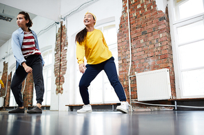 Two young modern female performers in activewear training in studio or gym