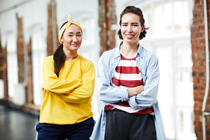 Happy young women in activewear crossing their arms on chest in front of camera