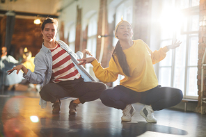 Two girls sitting on squats while doing hip hop or breakdance exercise in studio