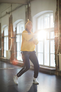 Contemporary active girl performing breakdance exercise while training in modern studio