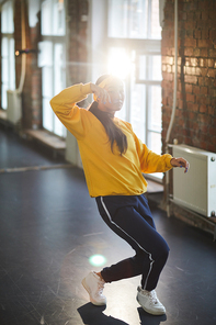 Teenage girl in activewear training breakdance on the floor of modern studio of dancing