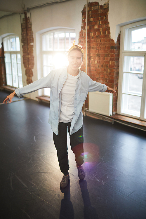 Young dancer in activewear training in studio of modern dance in front of camera