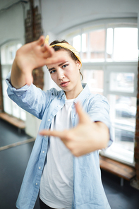 Young female in activewear making frame by hands while  from between