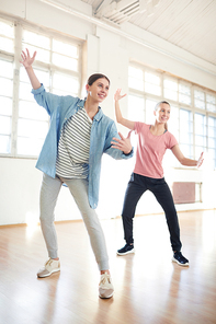 Active girls repeating exercise after coach while practicing sports dancing in modern studio