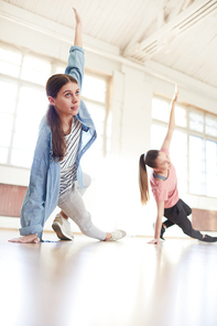 Active girls performing dance exercise or move after their coach at lesson of modern breakdance in studio