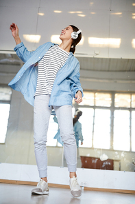 Happy young breakdancer with headphones exercising in large modern studio of leisure center