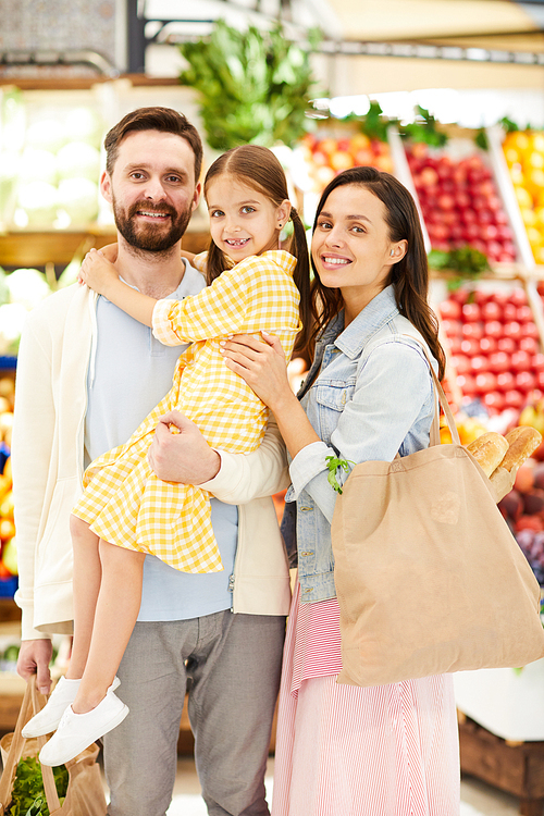 Optimistic young family in casual clothing standing against food stall and , they enjoying shopping together in supermarket