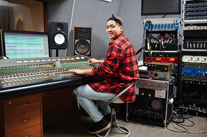 Young woman in casualwear  while mixing sounds in audio studio