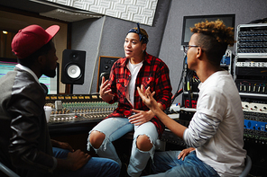 Sound operators talking to young musician in audio studio before recording songs