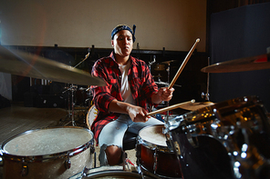 Young modern female musician playing drums in studio of records