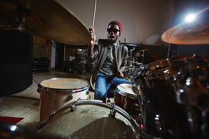 Young drummer and participant of popular band playing drums in studio during repetition