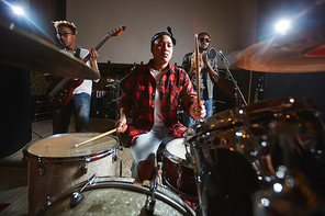 Female drummer, guitarist and singer preparing for public performance in studio