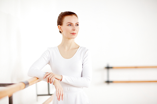 Adult ballerina with blue eyes an white clothes looking away in light dancing school