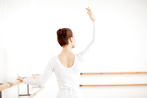 Adult graceful ballerina dancing ballet in light white studio and staying back