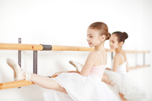 Little ballerinas practicing dances at wooden machine and smiling side view