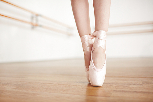 Faceless ballerina doing exercises in pointe champagne color in light studio