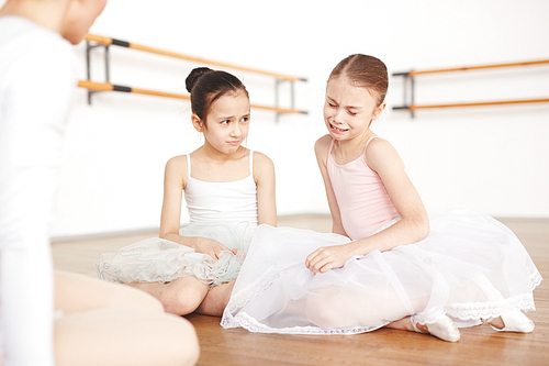 Girls with strict hairstyle and white tutu listening critic of teacher and crying in dancing school