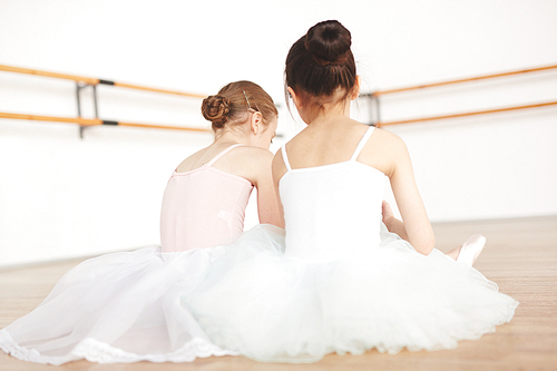 Rear view of little ballerinas having rest on the floor between classes of dancing