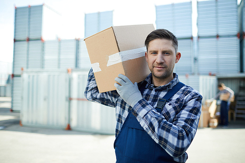 Young man with large box  while carrying load to storehouse