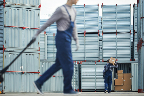 Two loader men working outdoors and removing cargo in storage containers