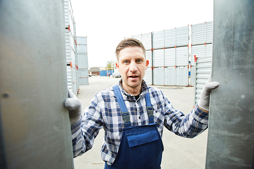 Shocked emotional handsome worker in overall opening metal container and discovering burglary at cargo storage area