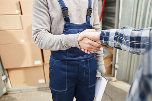 Close-up of unrecognizable men concluding agreement about container rent and shaking hands outdoors