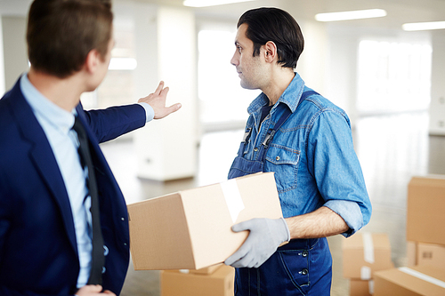 Businessman showing worker where to put box with supplies during relocation to new office