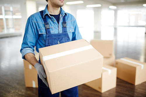 Gloved worker in uniform carrying packed box with supplies while doing his work during relocation