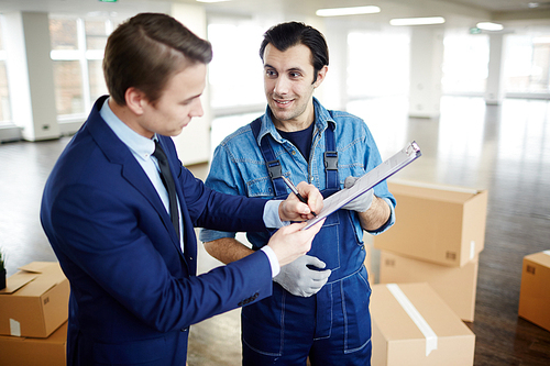 Young businessman signing document held by load worker after carrying out his work