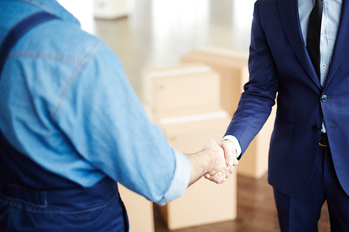 Handshake of businessman in suit and worker in uniform after help with relocation to new office