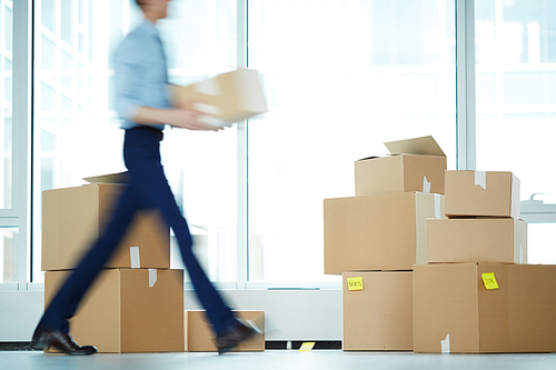 Blurry motion of businessman carrying boxes from one office to another during relocation
