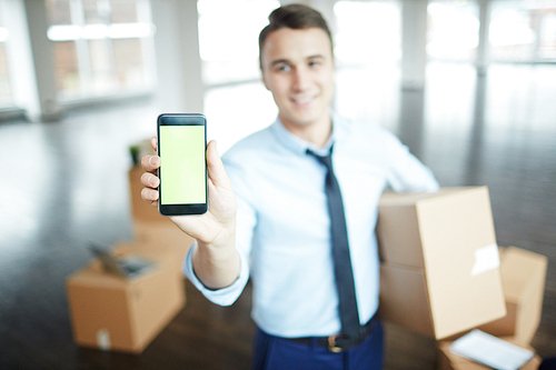 Young modern businessman with box showing advert of delivery service center in his smartphone
