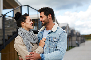 Happy beautiful young couple in love standing outdoors and hugging each other while looking into eyes