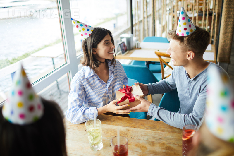 유토이미지 | Happy guy congratulating his girlfriend on birthday while sitting in cafe with friends