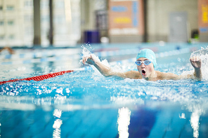 Professional swimmer splashing water while swimming energetically towards finish