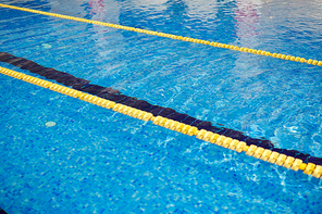 Background image of rippling clear blue water in swimming pool with yellow line on surface