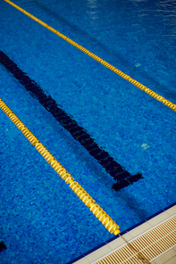 High angle background image of clear blue water in empty swimming pool with lanes and lines