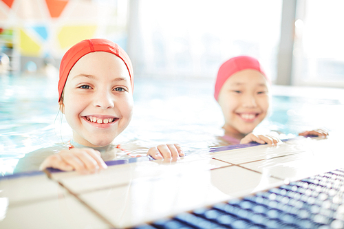 Cute smiling friendly girls in swim-caps  out of water