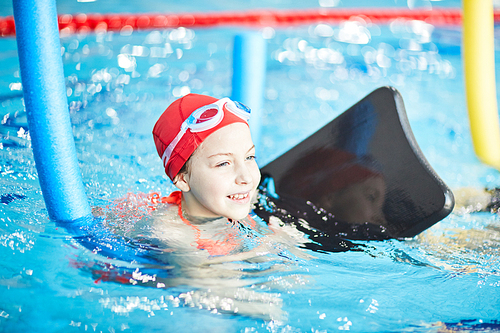 Adorable girl in swimwear practicing swimming with special resistance equipment