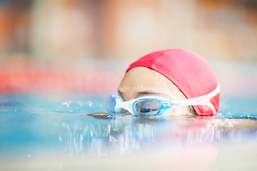 Top of human head in swimwear can be seen during training in water