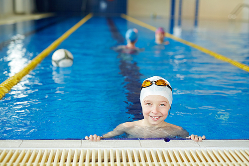 Little champion smiling brightly  taking a break from polo team practice in swimming pool