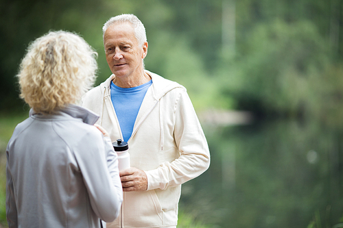 Two senior active people having talk in natural environment after workout